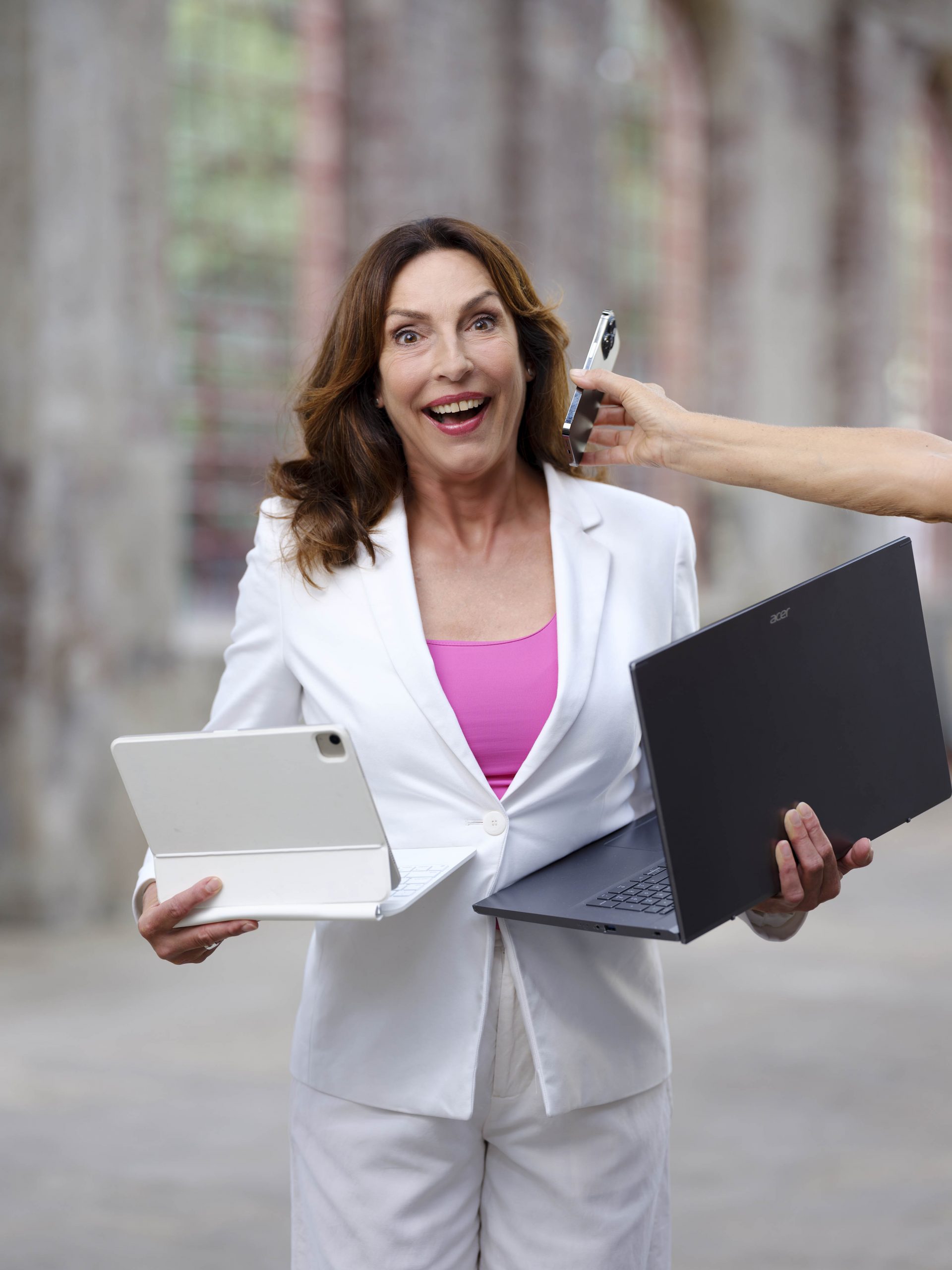 Porträt von Andrea Volk mit ihrer Arbeitsausstattung: Laptop, Tablet und Handy