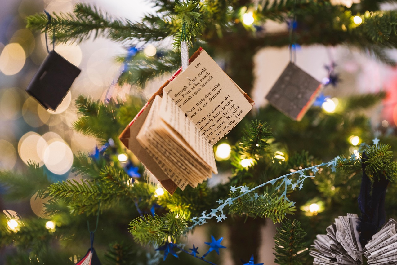 Auf dem Bild ist ein Weihnachtsbaum zu sehen, der anstatt Kugeln kleine Mini-Bücher als Dekoration trägt.